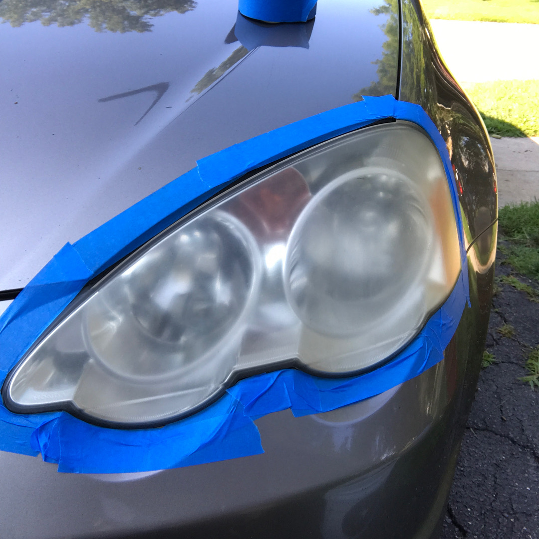 Clouded, oxidised headlight lens masked off before restoration